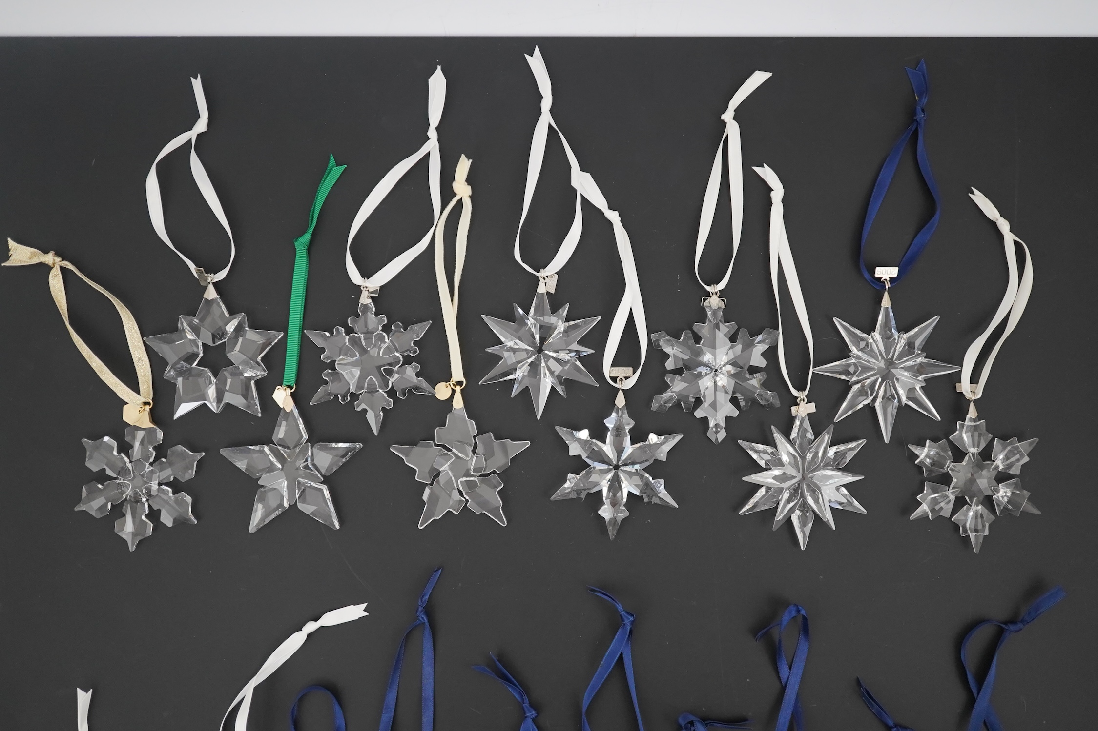 Twenty one Swarovski Christmas stars with hanging ribbons and date charms, No boxes but otherwise in all good in condition